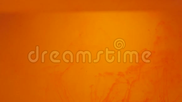 橙色粒子在橙色背景上上升墨水颜料混合在水中缓慢地向上移动抽象油墨背景视频的预览图