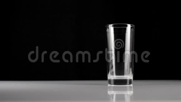 新鲜的白牛奶倒在白色桌子上的透明玻璃上背景是黑色的呆在家里的概念视频的预览图