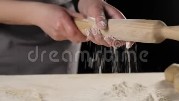 专业的面包师用面粉擦拭擀面杖用于在木桌上擀面团面团揉捏的概念视频的预览图