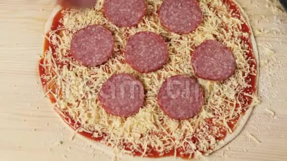 专业厨师把切片的腊肠放在上面放在烤的披萨奶酪上上面有番茄酱上面有披萨视频的预览图
