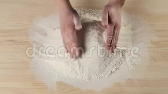 专业的面包师用手把面粉耙在一张木桌上然后在一堆面粉中加深面团揉捏的概念视频的预览图