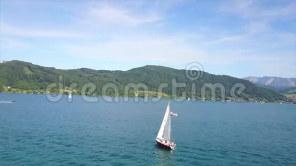 空中摄影一艘帆船在蓝色的湖面上可以看到欧洲的山脉和天空视频的预览图