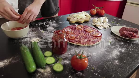 年轻女孩的手把番茄放在披萨面团上视频的预览图