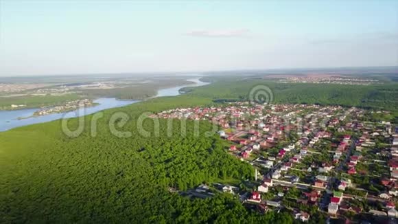 阳光明媚的夏日在茂密的森林和河流附近的一个小山村进行空中摄影视频的预览图