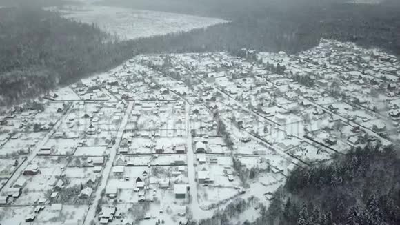 下雪时飞过森林里的村庄视频的预览图