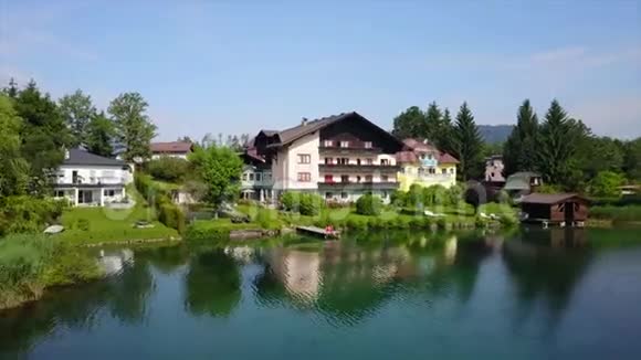 空中拍摄一座美丽的大房子湖边被其他房子和青山环绕视频的预览图