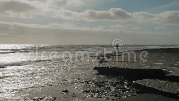 一个孤独的人在波涛汹涌的海洋的海岸上的剪影浪漫孤独的概念视频的预览图