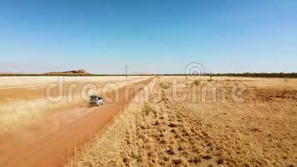 当无人驾驶飞机上升时越野汽车沿着沙漠道路行驶的速度揭示干旱的景观视频的预览图
