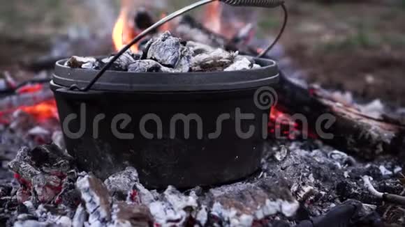 在明火上热气腾腾的黑铸铁锅关闭慢动作视频的预览图