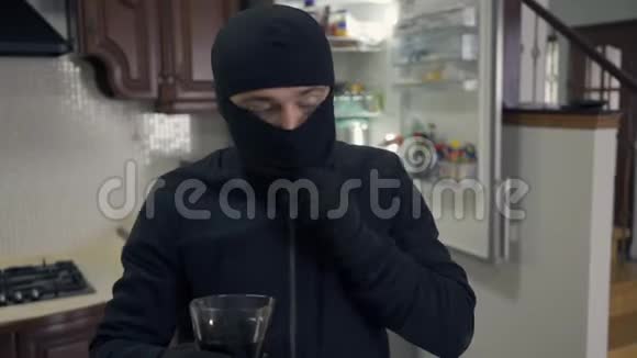 一幅年轻的白种人小偷穿着黑色衣服巴拉克拉瓦从杯子里喝酒的肖像偷东西的家伙视频的预览图