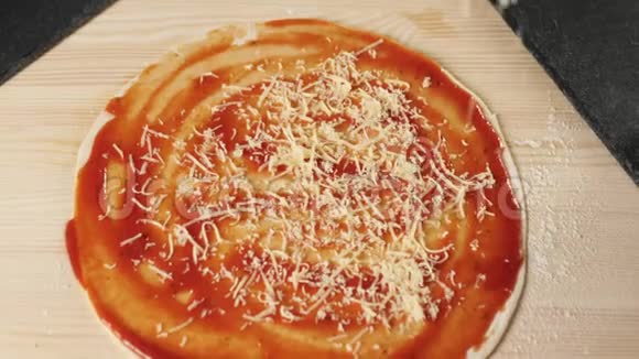 专业厨师将磨碎的奶酪倒入一个披萨基地桌子上放着番茄酱上面装饰着披萨配料视频的预览图