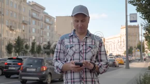 一个白人男子站在街上手里拿着智能手机的咔嚓声塞进口袋里视频的预览图