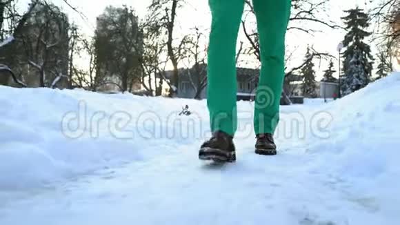 在阳光明媚的冬日男人在城市公园的雪中漫步视频的预览图