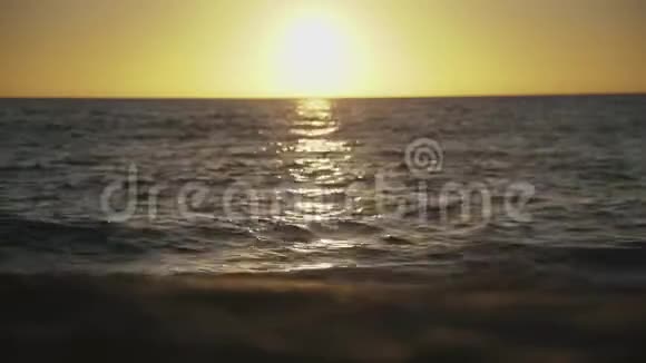 海水的夕阳映照在海滩和水面上视频的预览图