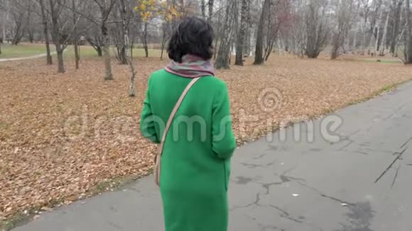 慢动作白种人中年妇女在公园散步秋天主要是多云的公园视频的预览图