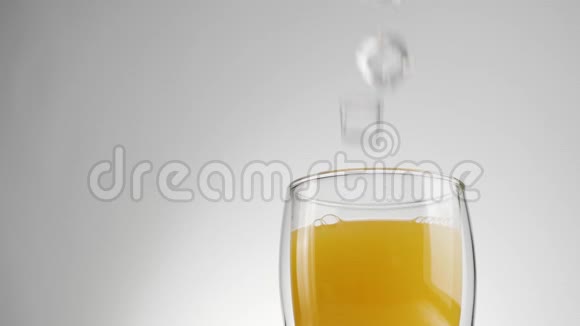 冰块溅起气泡放入新鲜的橙汁或菠萝汁放入双壁杯中视频的预览图