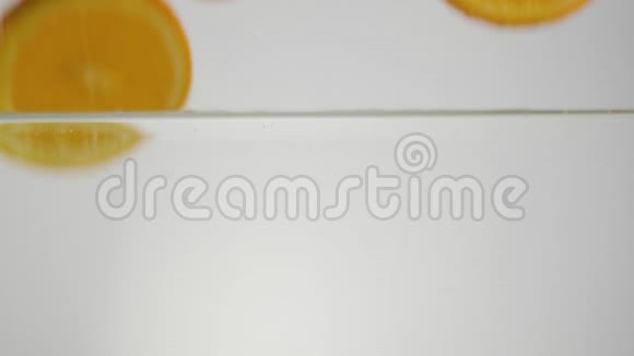 新鲜的橙色切片随着飞溅和气泡进入水中的光背景健康食品的概念视频的预览图