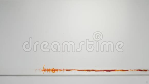 橙色粒子在白色背景上上升墨水颜料混合在水中缓慢地向上移动抽象油墨背景视频的预览图