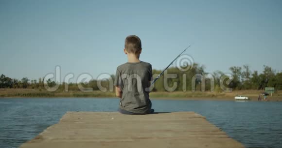 那个男孩正在河上的旧码头上钓鱼视频的预览图