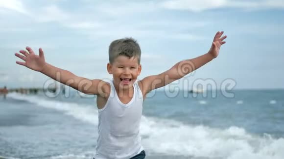 微笑的男孩在海岸边的海浪中奔跑的画像视频的预览图