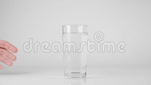 手拿一杯纯淡水从白色的桌子在白色的背景下呆在家里吃健康食品的观念视频的预览图