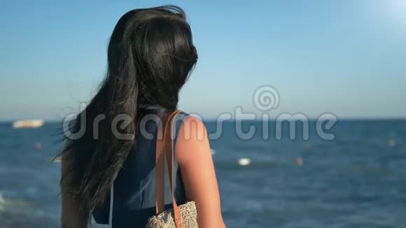 时尚的黑发女人微笑着转过头在海边玩头发的肖像视频的预览图