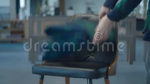 女性手在舒适的皮革木椅上放置格子绿色着色格子背景模糊的木制家具视频的预览图