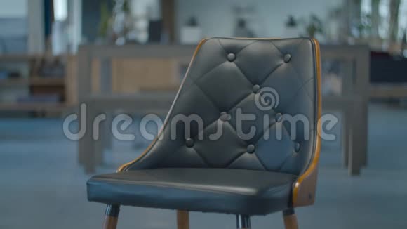 女性手把笔记本电脑放在黑色皮革木扶手椅上站在镜头中间模糊的木制家具视频的预览图