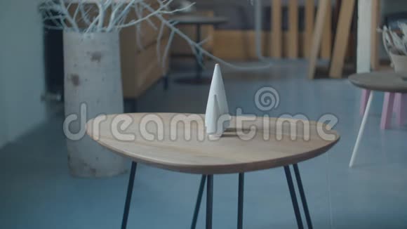 手把白色木制圣诞树玩具放在木制桌子上桌子上有三个白色锥形木制玩具视频的预览图