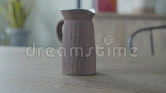 女性手把带苔藓的锅放在木桌上陶瓷茶壶放在简约的室内公寓里视频的预览图