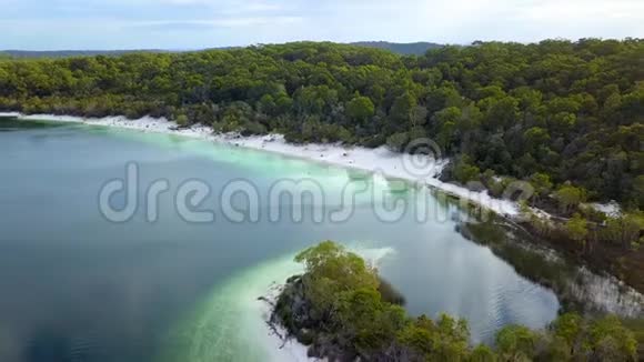 空中原始的白色沙滩和淡水湖被茂密的绿色森林包围着视频的预览图
