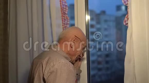 戴眼镜的老人看着窗外关上窗帘视频的预览图