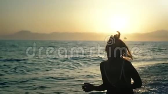穿着泳装在海滩上奔跑享受日落自由的快乐女孩的特写剪影视频的预览图