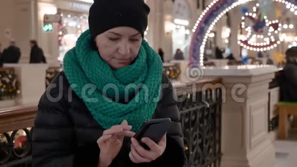 白种人中年妇女坐在室内购物中心她可以发短信视频的预览图