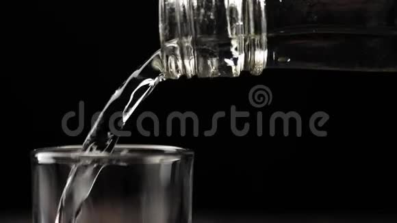 用手将伏特加龙舌兰酒或清酒倒入黑色桌子上的空杯中置于黑色背景下视频的预览图