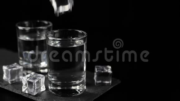 冰块倒下来溅起水花和气泡装有冰块的黑板上用伏特加龙舌兰酒或清酒泡成玻璃杯视频的预览图