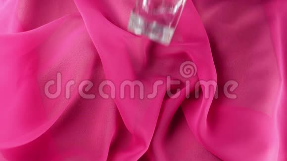 带有青色香水或精油的扁平表面瓶落在粉红色织物背景上香气和气味的概念视频的预览图
