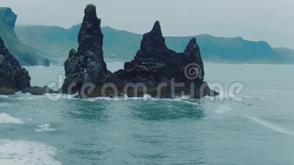 空中无人驾驶飞机拍摄黑色沙滩上的岩石视频的预览图
