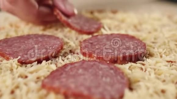 专业厨师把切片的腊肠放在上面放在烤的披萨奶酪上上面有番茄酱上面有披萨视频的预览图