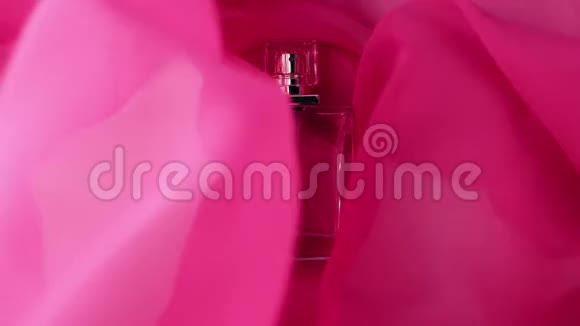 平面瓶与青色香水或精油是在粉红色的布上粉红色的织物在周围飘来飘去在周围荡来荡去视频的预览图