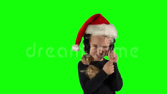 女孩用耳机听音乐和跳舞带圣诞帽的滑稽孩子视频的预览图