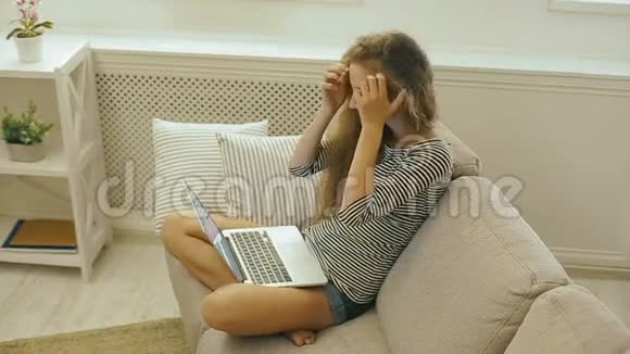 带着笔记本电脑坐在沙发上的快乐少女青少年使用社交网络在网上商店购物视频的预览图