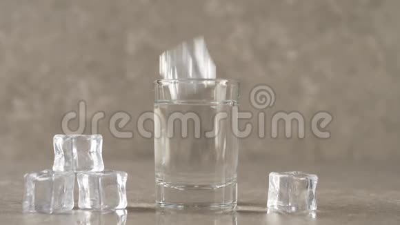 冰块倒在大理石桌面上溅起水花和气泡放入盛有伏特加龙舌兰酒或清酒的酒杯中视频的预览图
