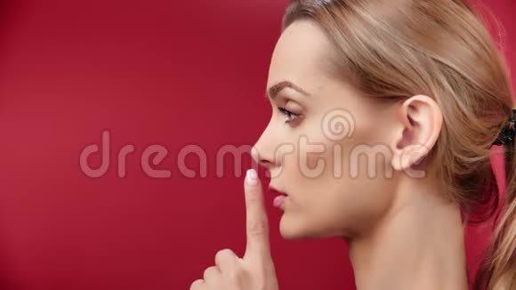特写可爱的年轻女性秘密地把食指放在唇边视频的预览图
