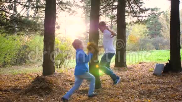 一个少年和一个孩子玩在公园里绕着一棵树跑追上他太阳光线穿透了松树视频的预览图
