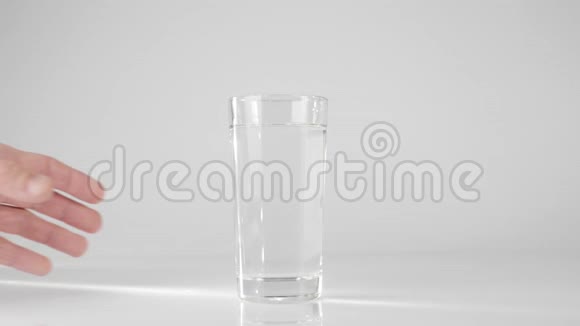 手拿一杯纯淡水从白色的桌子在白色的背景下呆在家里吃健康食品的观念视频的预览图