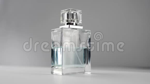 带有青色香水或精油的扁平表面瓶在灰色背景下慢慢旋转在白色桌子上视频的预览图