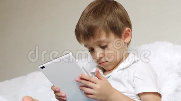 一个男孩看着平板电脑屏幕用手指触摸触摸屏的肖像孩子用的是平板电脑视频的预览图