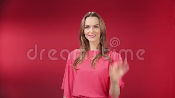 微笑的金发美女在红色工作室背景下展示ok手势视频的预览图