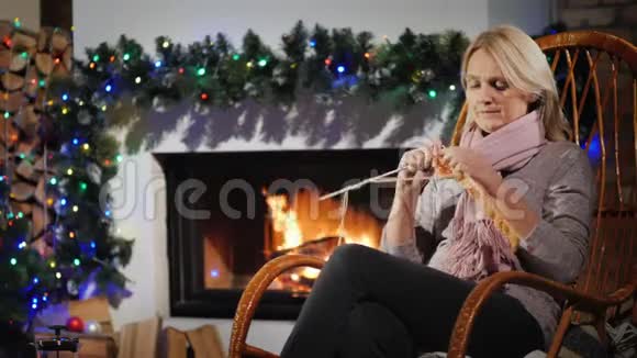 在一个冬天的夜晚休息一个女人在一个装饰圣诞节的壁炉旁编织视频的预览图